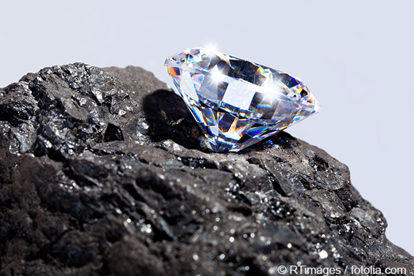 Nahaufnahme eines funkelnden geschliffenen Diamants, der auf einem dunklen Stein positioniert ist. Bildquelle: RTimages / Fotolia.com