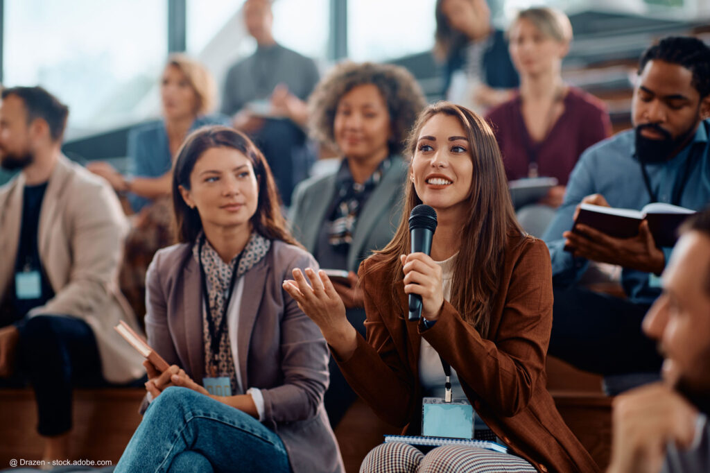 Frau spricht während einer Konferenz in ein Mikrofon. Bildrechte: Drazen - stock.adobe.com